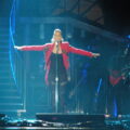 alicia keys net worth, music, business & family 5 alicia keys singing at a microphone with outstretched arms in a red jacket, arena di verona, may 2010