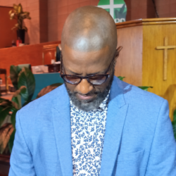 Rickey Smiley in a blue blazer at New Mount Olive Baptist Church in December 2024